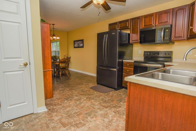 kitchen with appliances, a sink, light countertops, a ceiling fan | Image 6