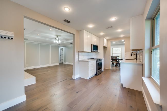 Kitchen with light wood finished floors, appliances with stainless steel finishes, light countertops, decorative backsplash, and recessed lighting | Image 13