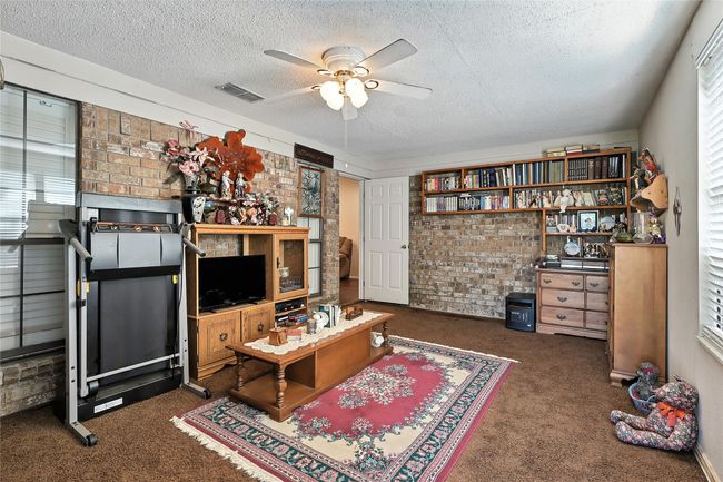 Carpeted living room with brick wall, a textured ceiling, and ceiling fan | Image 22