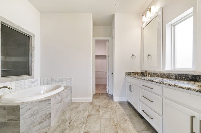 Bathroom featuring a spacious closet, vanity, baseboards, and a bath | Image 18