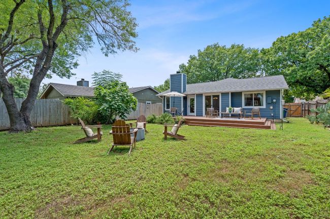 Rear view of property featuring a fenced backyard, a wooden deck, a chimney, and outdoor lounge area | Image 35