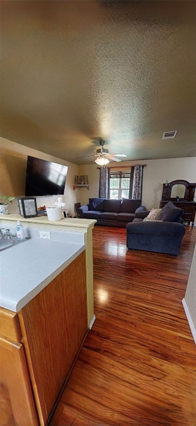 Living room featuring wood finished floors, a textured ceiling, and a ceiling fan | Image 13