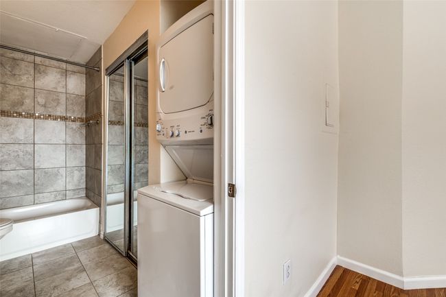 Laundry area with tile patterned floors, baseboards, stacked washing maching and dryer, and laundry area | Image 16