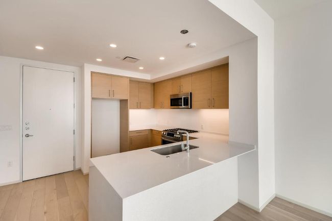 Kitchen with stainless steel appliances, light countertops, light wood-style floors, recessed lighting, and a peninsula | Image 6