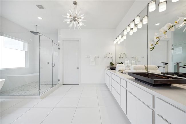 PRIMARY BATHROOM: Epitome of luxury.. the primary bathroom of this modern home, where stunning white tile details elevate the space to a new level of sophistication. Every element of this spa-like retreat is meticulously designed to provide both indulgence and functionality. The sleek, minimalist design is complemented by high-end fixtures and finishes, including sleek faucets, a spacious vanity with ample storage. | Image 33
