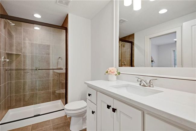 Bathroom featuring toilet, visible vents, tile patterned flooring, a shower stall, and vanity | Image 53