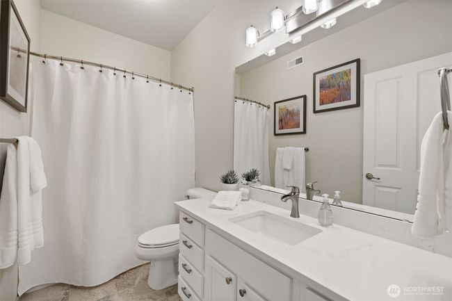 Main bath with newer vanity, quartz counter, new lighting and tile floor | Image 32