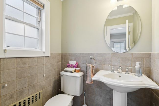 Bathroom with tile walls, crown molding, radiator heating unit, and toilet | Image 15