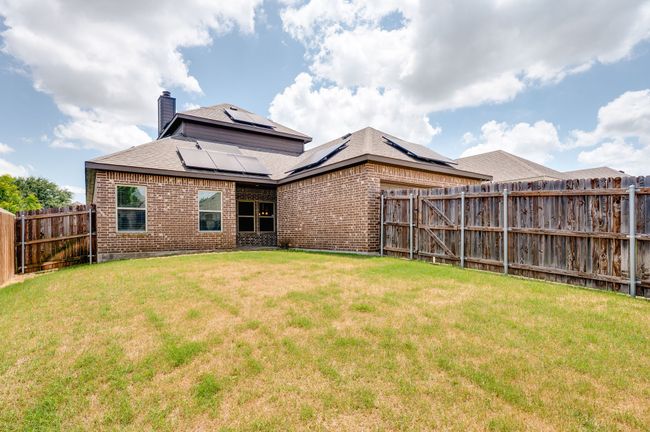 Back of house featuring brick siding, a chimney, a fenced backyard, and solar panels | Image 26