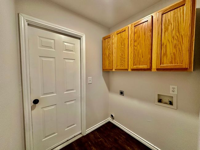 Washroom with hookup for an electric dryer, cabinet space, hookup for a washing machine, and dark wood finished floors | Image 17