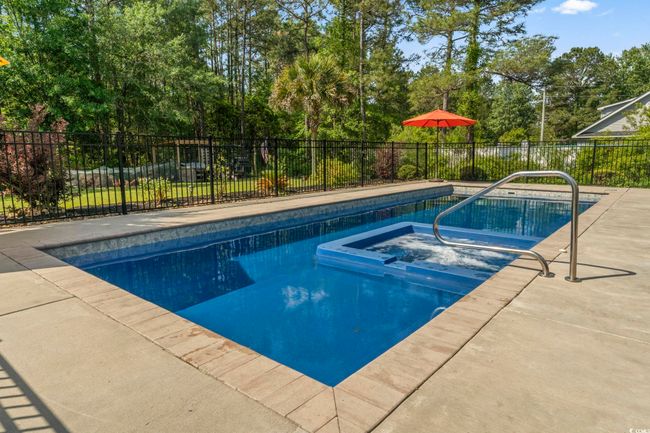 View of pool featuring a patio area, fence, and a pool with connected hot tub | Image 34