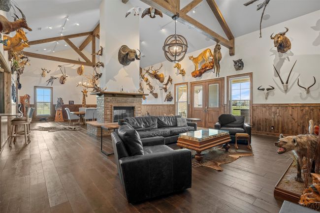 Living room with high vaulted ceiling, a wainscoted wall, beam ceiling, dark wood-style flooring, and a chandelier | Image 4