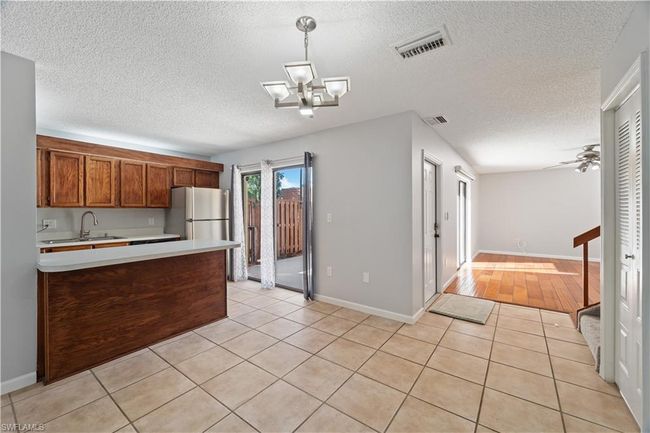 Kitchen with visible vents, a sink, light countertops, freestanding refrigerator, and a textured ceiling | Image 5