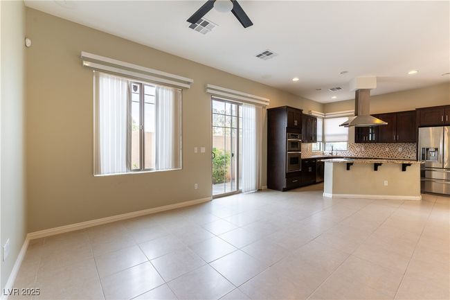 Kitchen featuring a breakfast bar area, island range hood, stainless steel appliances, decorative backsplash, and ceiling fan | Image 12