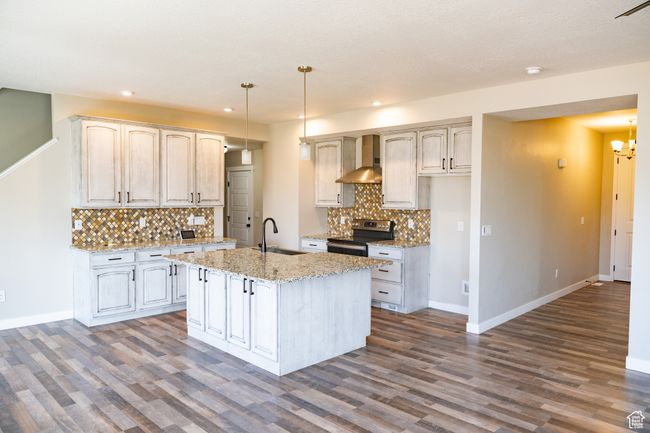 Kitchen featuring stainless steel electric stove, wall chimney range hood, dark wood-style floors, tasteful backsplash, and recessed lighting | Image 6