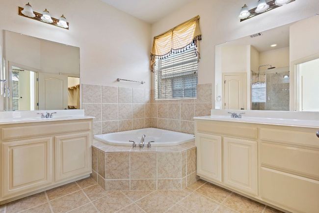 Bathroom with a tile shower, tile patterned floors, visible vents, two vanities, and a garden tub | Image 20