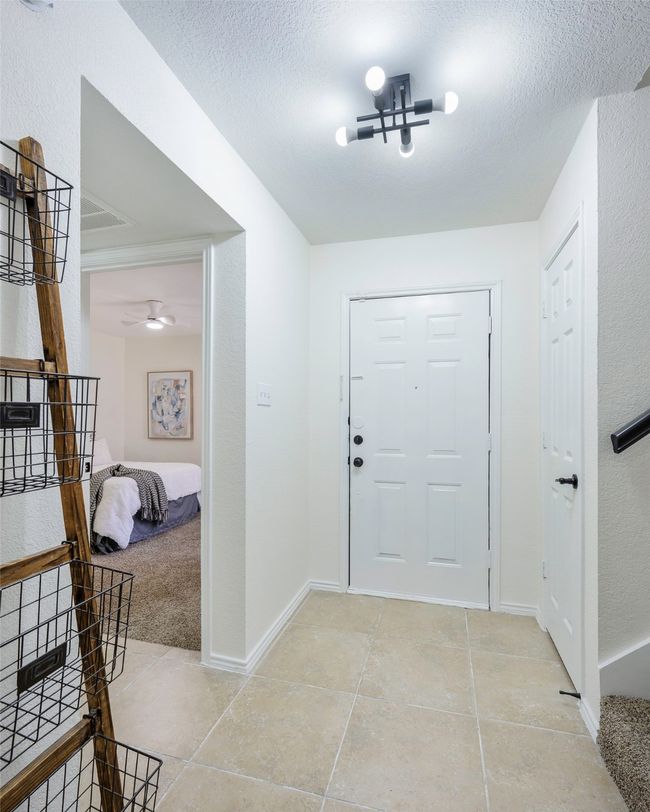 Foyer entrance with ceiling fan, light tile patterned floors, baseboards, and a textured ceiling | Image 4