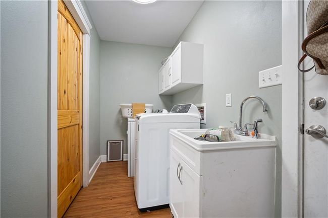 Laundry room featuring baseboards, washing machine and clothes dryer, a sink, light wood finished floors, and cabinet space | Image 27