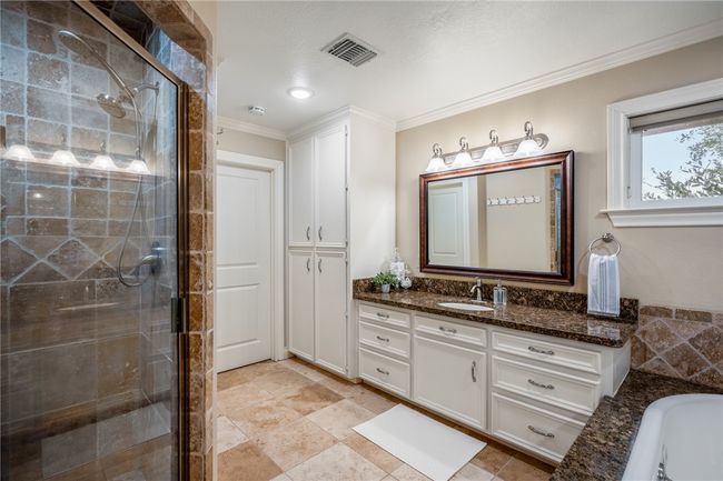 Bathroom with a bathtub, visible vents, ornamental molding, a stall shower, and vanity | Image 37