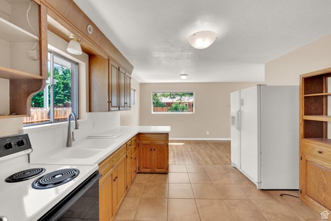 Kitchen featuring white refrigerator with ice dispenser, open shelves, range with electric stovetop, and plenty of natural light | Image 6