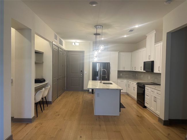 Kitchen featuring black appliances, backsplash, white cabinetry, light stone countertops, and recessed lighting | Image 8