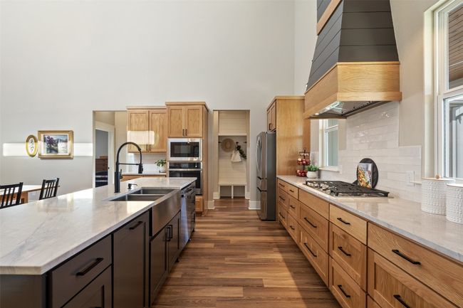 Kitchen with appliances with stainless steel finishes, a sink, a high ceiling, premium range hood, and dark wood-style floors | Image 11