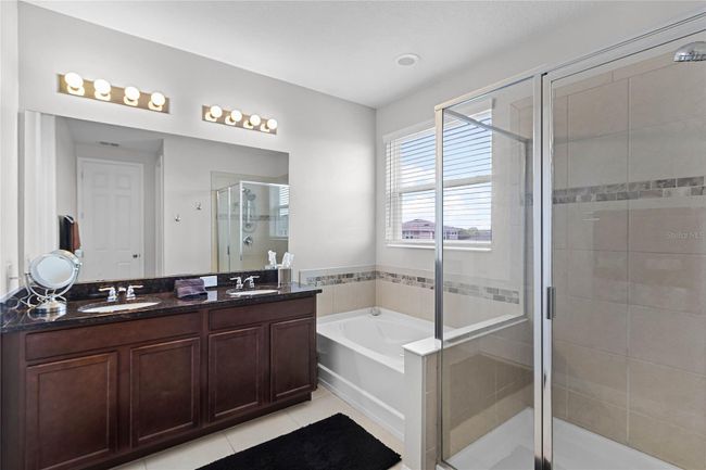 primary bath with soaking tub, a glass-enclosed shower, a double sink vanity, and a large walk-in closet. | Image 27