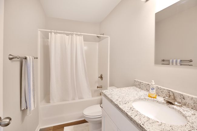 Bathroom featuring vanity, shower / bathtub combination with curtain, and wood finished floors | Image 8