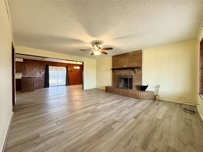 Unfurnished living room with a brick fireplace, a textured ceiling, light hardwood / wood-style floors, and ceiling fan | Image 15
