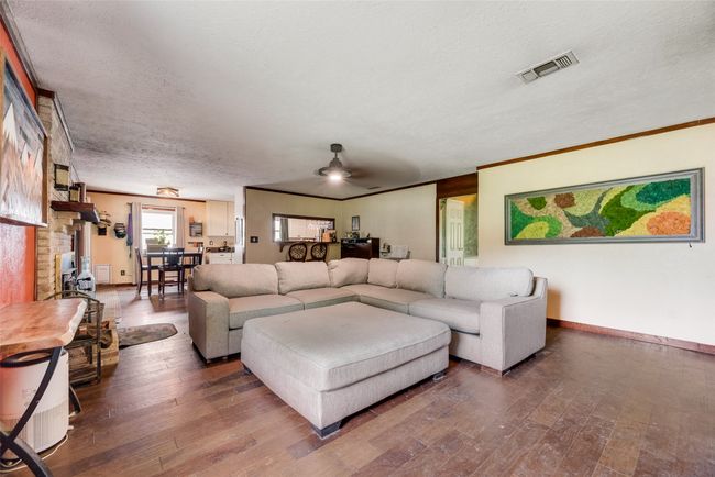 Living area with visible vents, a textured ceiling, baseboards, and hardwood / wood-style flooring | Image 8