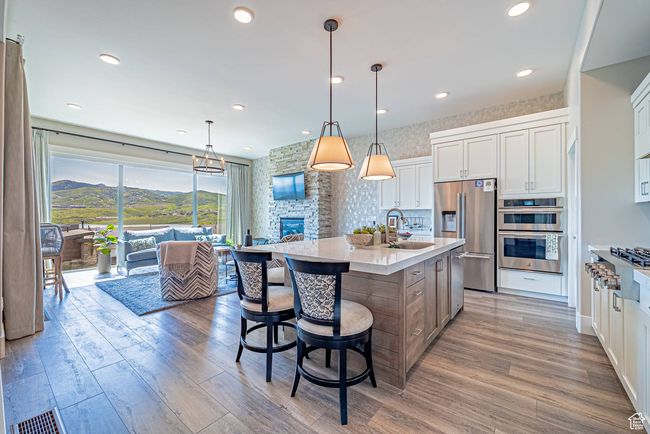 Kitchen featuring stainless steel appliances, a sink, light countertops, light wood-style flooring, and white cabinets | Image 9