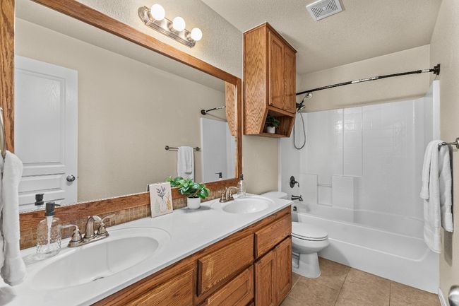Full bathroom with double vanity, shower / tub combination, tile patterned floors, and a textured ceiling | Image 25