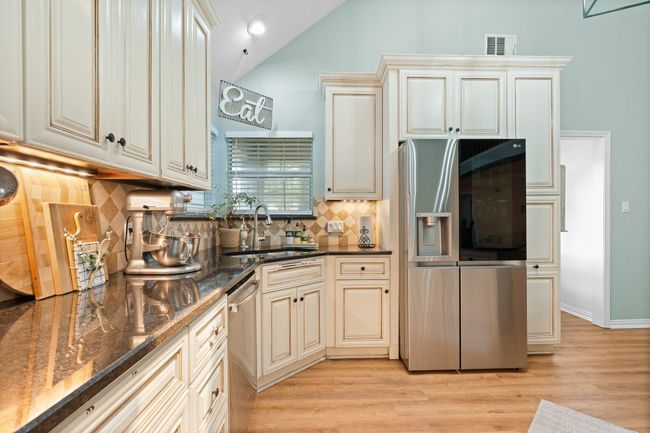 Kitchen with cream cabinetry, stainless steel appliances, lofted ceiling, light wood-style flooring, and backsplash | Image 8