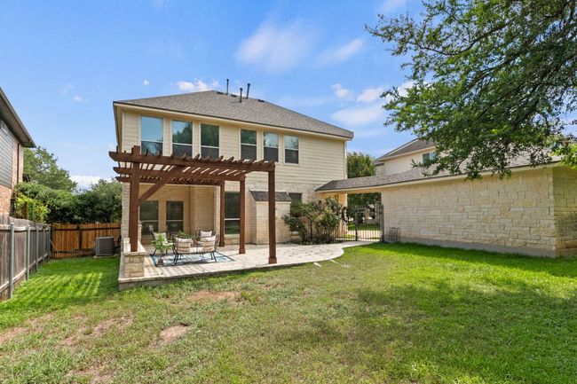Back of house with a pergola, a fenced backyard, stone siding, a patio, and a gate | Image 35