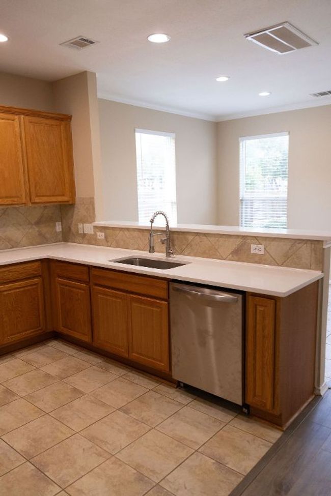 Kitchen featuring stainless steel dishwasher, a sink, brown cabinets, crown molding, and breakfast bar. | Image 7
