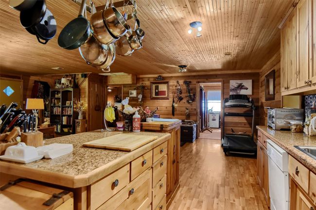 Kitchen featuring light countertops, wood ceiling, wooden walls, white dishwasher, and light wood-style floors | Image 21