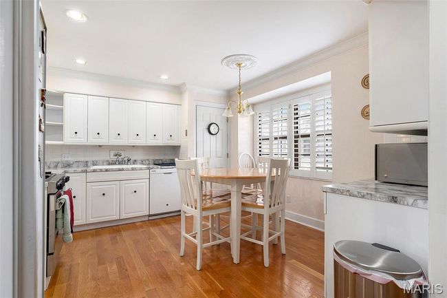 Kitchen with ornamental molding, dishwasher, white cabinetry, light wood-style floors, and gas stove | Image 6