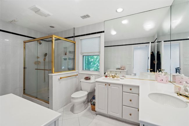 Bathroom featuring a stall shower, tile patterned floors, toilet, and double vanity | Image 19