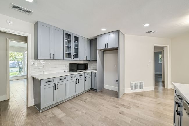 Kitchen featuring visible vents, light countertops, and stainless steel microwave | Image 12