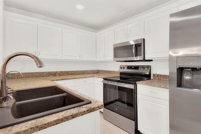 Kitchen with stainless steel appliances, white cabinetry, light countertops, recessed lighting, and light tile patterned flooring | Image 9