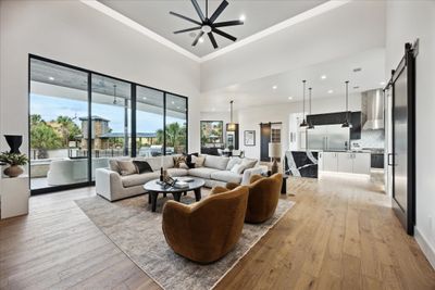 Experience the perfect blend of warmth and elegance in this living room, where a cozy fireplace and panoramic views create an inviting and serene atmosphere, seamlessly opening to a stylish kitchen. | Image 3