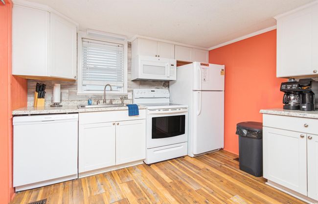 Kitchen featuring white appliances, backsplash, white cabinetry, crown molding, and light wood-style flooring | Image 12