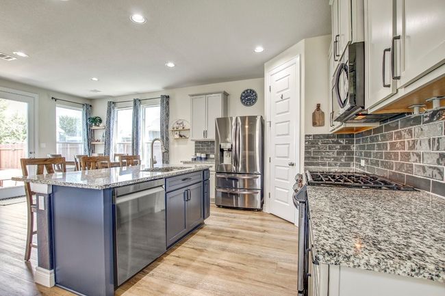 Kitchen with stainless steel appliances, a kitchen breakfast bar, light stone counters, recessed lighting, and light wood-style floors | Image 10