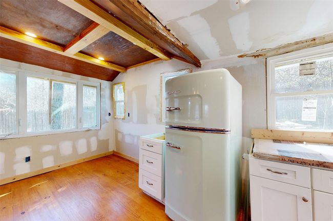 Kitchen with white cabinetry, fridge, light wood finished floors, and lofted ceiling with beams | Image 16