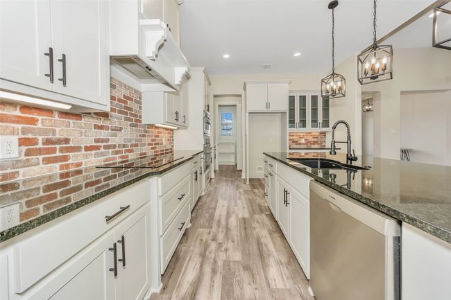Kitchen with backsplash, premium range hood, stainless steel dishwasher, a notable chandelier, and a sink | Image 11
