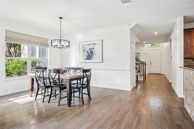 Dining space with wood finished floors, baseboards, a chandelier, and crown molding | Image 10