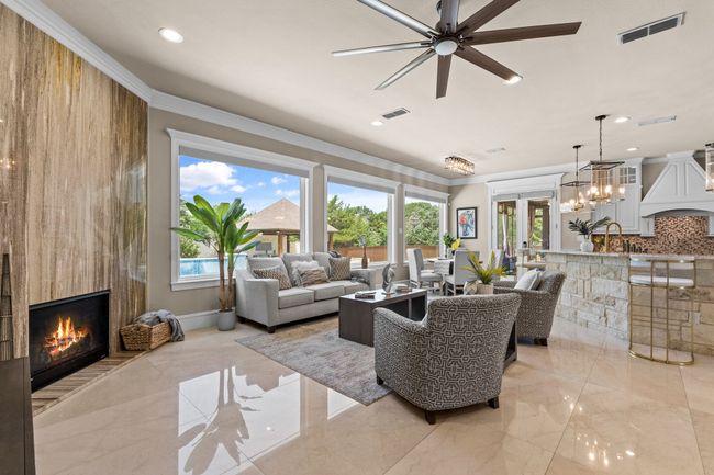 Living area with ceiling fan, a large fireplace, recessed lighting, crown molding, and french doors | Image 9