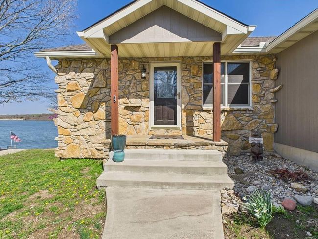 Doorway to property featuring stone siding and a water view | Image 4