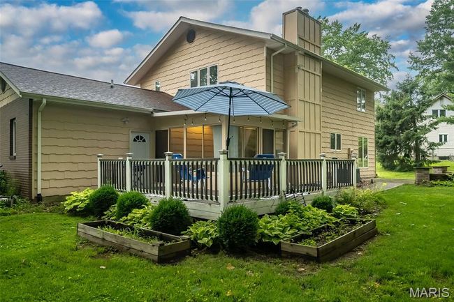 Back of house featuring a vegetable garden, a deck, a yard, a chimney, and roof with shingles | Image 36