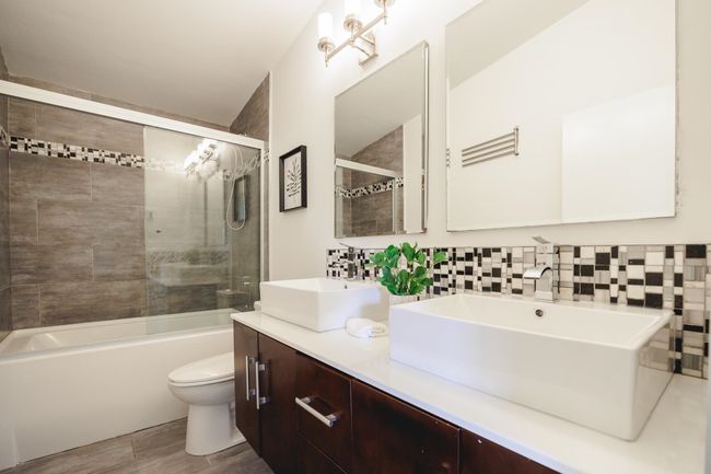Bathroom with double vanity, shower / washtub combination, wood finished floors, and decorative backsplash | Image 16